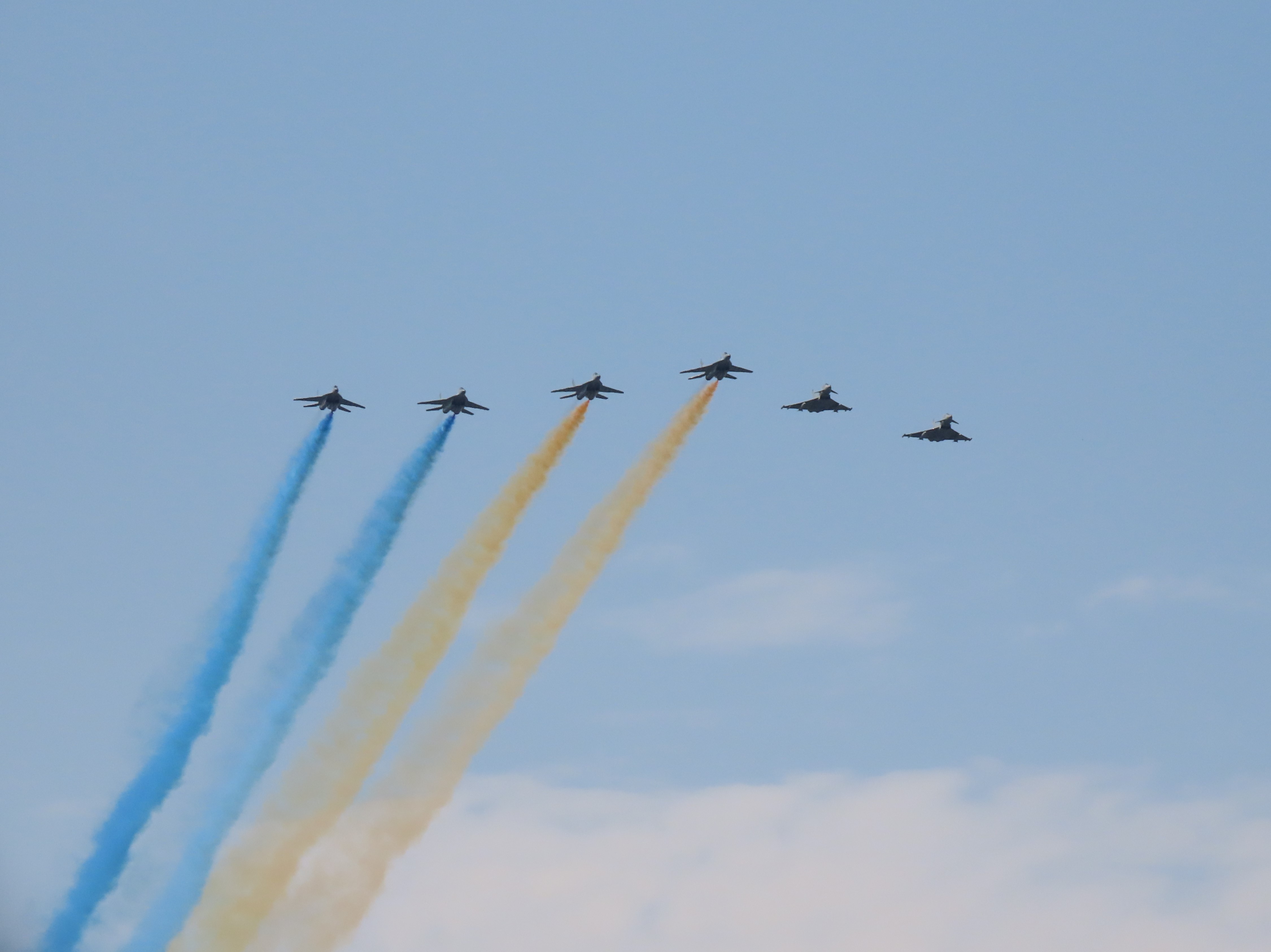 Image shows RAF Typhoons in flight trailing blue and yellow smoke in the colours of the Ukrainian flag.